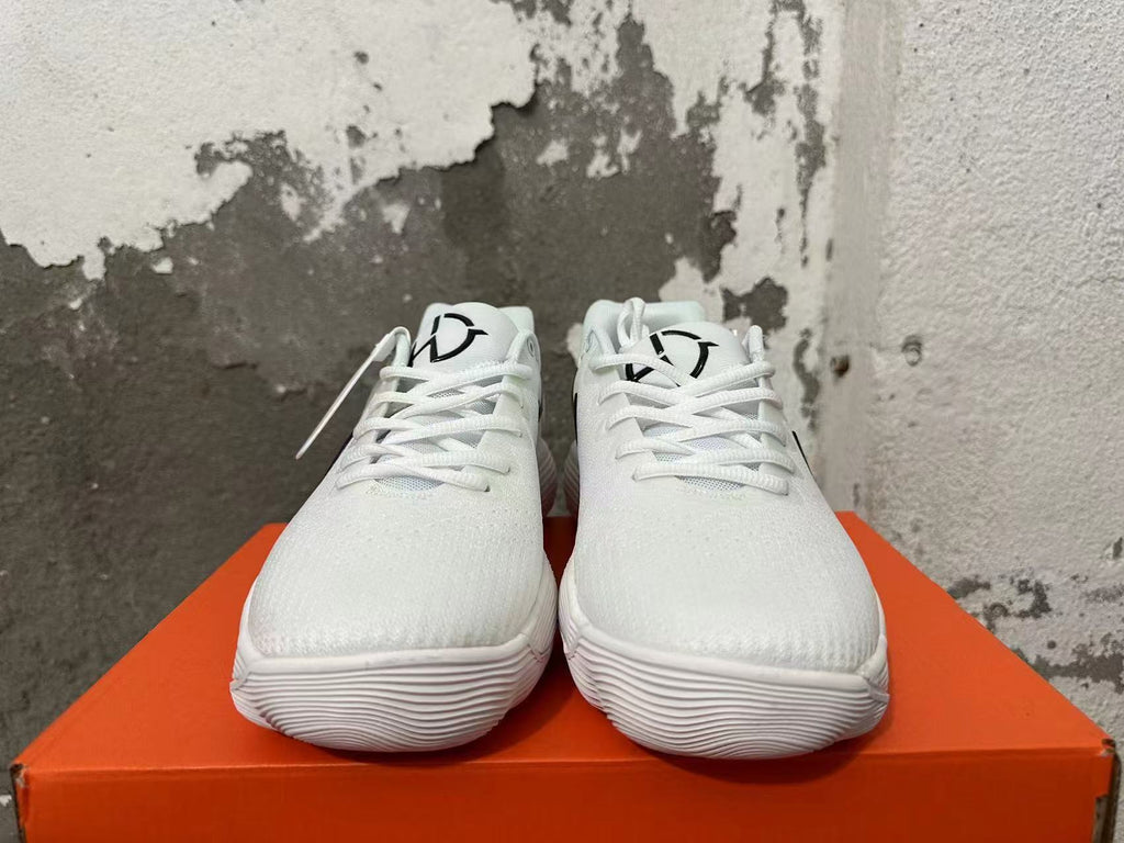Front view of white lace-up Nike shoes with black tongue graphics