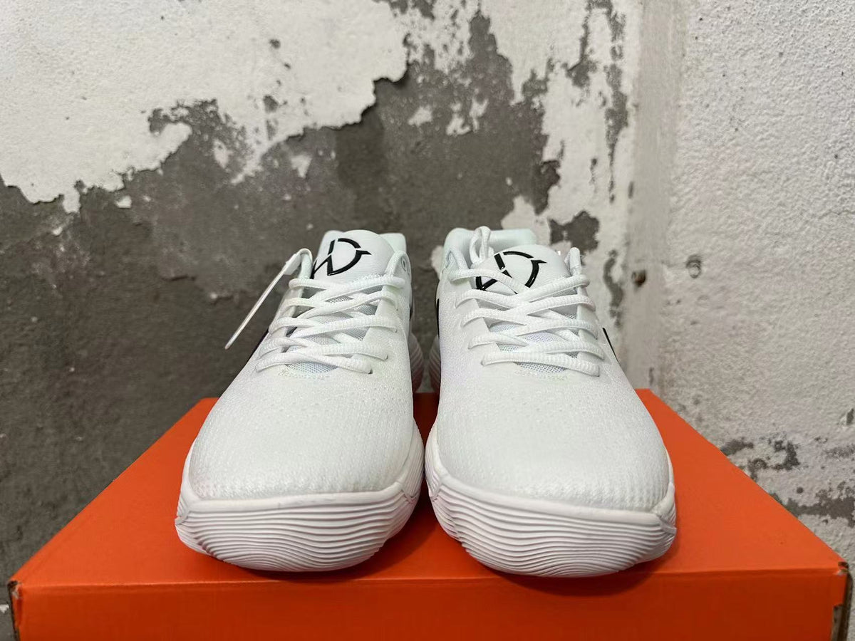 Front view of white lace-up Nike shoes with black tongue graphics