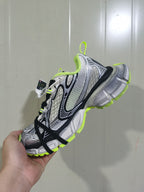 Angled view showing the sneaker’s layered upper, fluorescent-yellow collar and outsole accents, and black laces.
