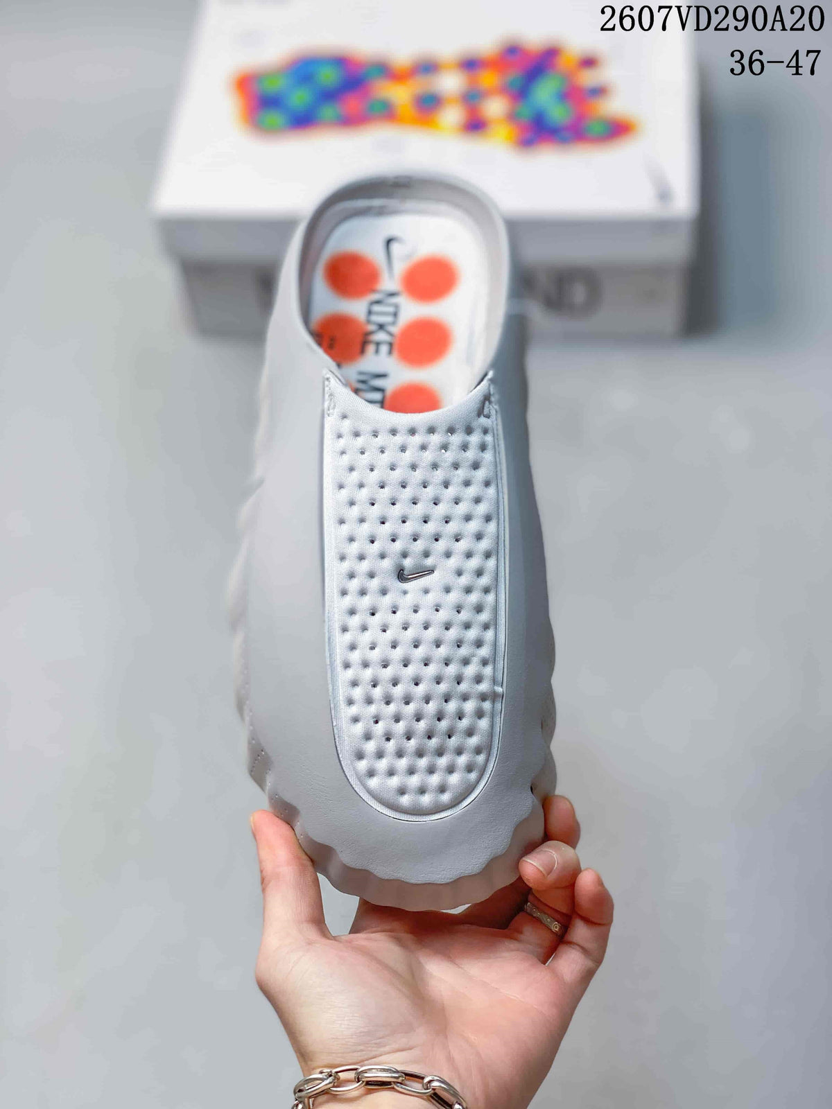 Top view of the white closed-toe slide sandal showing the perforated upper, Nike Swoosh, and orange footbed pods.