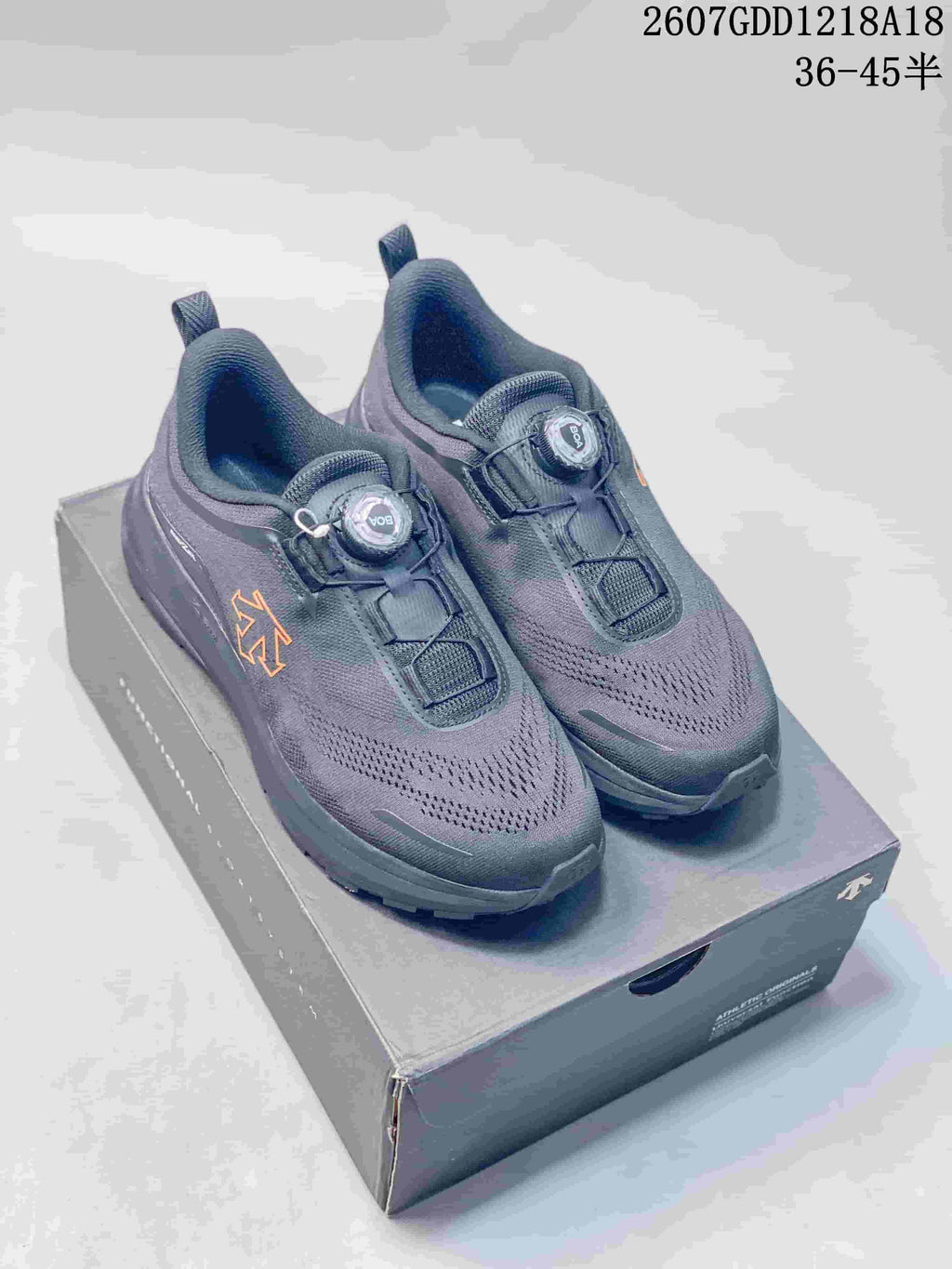 Pair of dark gray DESCENTE running shoes with BOA dial closures displayed on a shoebox; image text shows the model code and size range.