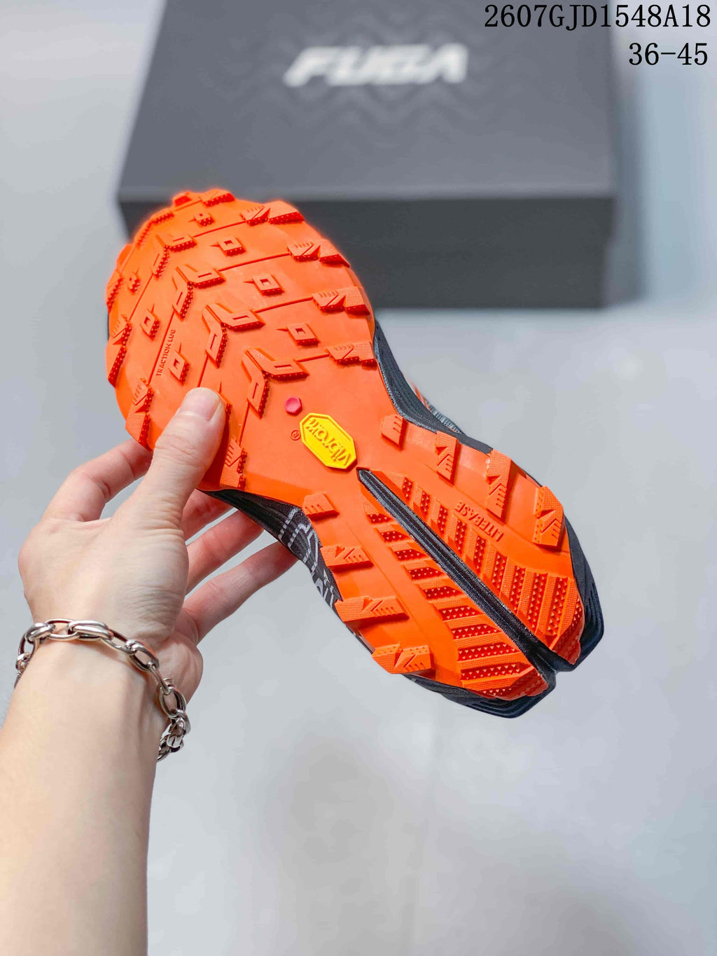Underside view showing the orange lugged outsole with Vibram branding and geometric traction patterns.