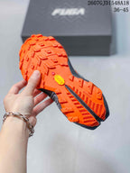 Underside view showing the orange lugged outsole with Vibram branding and geometric traction patterns.