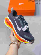Angled side view of the dark Nike running shoe showing the white swoosh, orange and yellow sole accents, and orange shoebox.