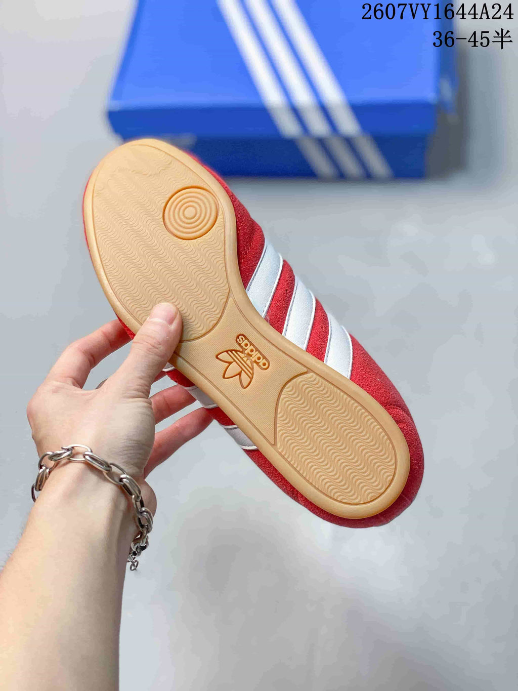Bottom view of a red adidas sneaker showing the gum-colored textured outsole and circular forefoot tread.