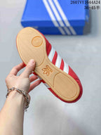 Bottom view of a red adidas sneaker showing the gum-colored textured outsole and circular forefoot tread.