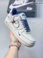 Angled side view of the white and blue low-top sneaker showing the Swoosh, heel branding, blue laces and white outsole.