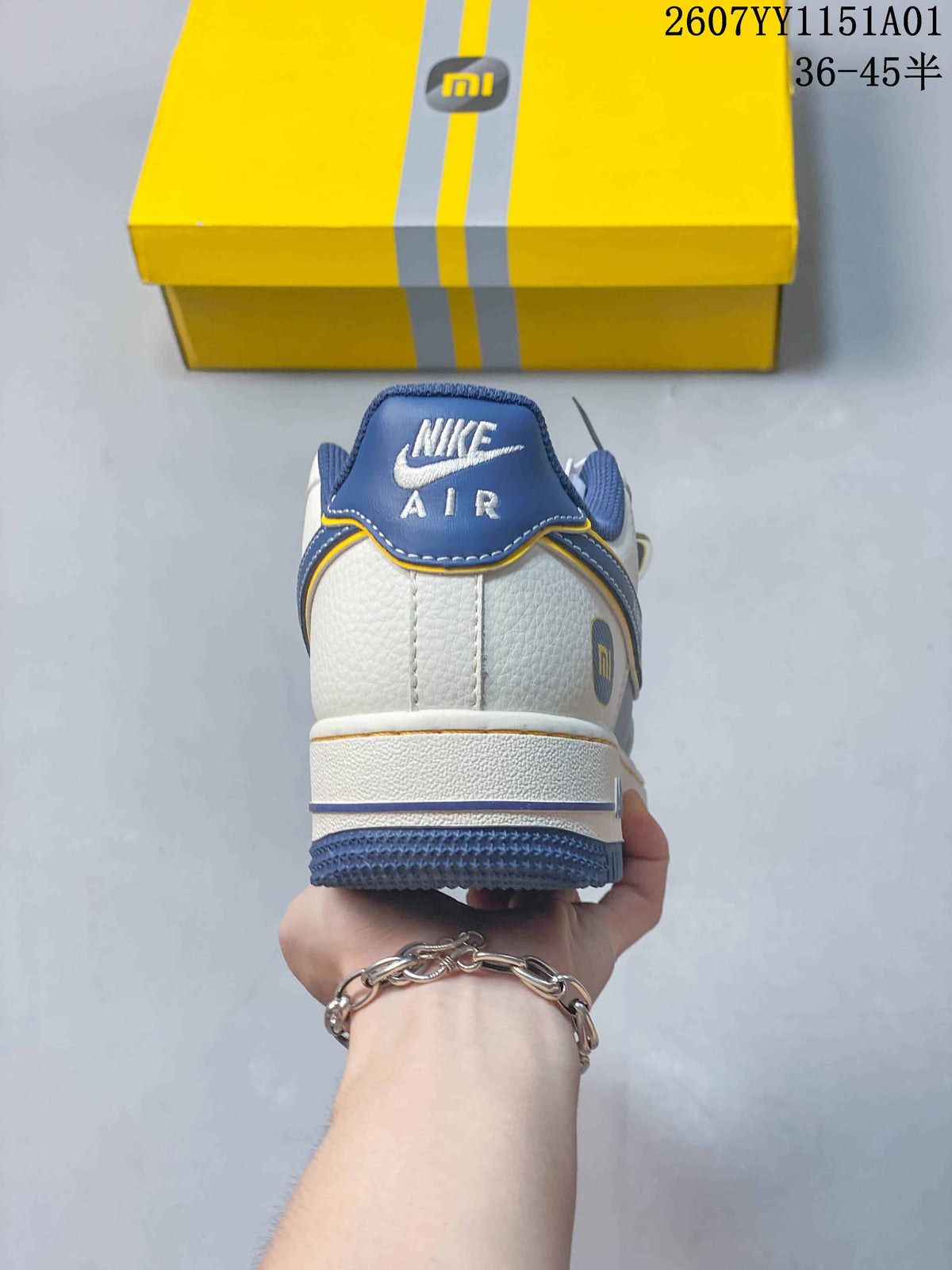 Rear view of the sneaker showing a blue heel tab and white upper.