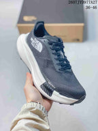 Angled side view showing the dark gray mesh upper, The North Face logo, white midsole, and black outsole.