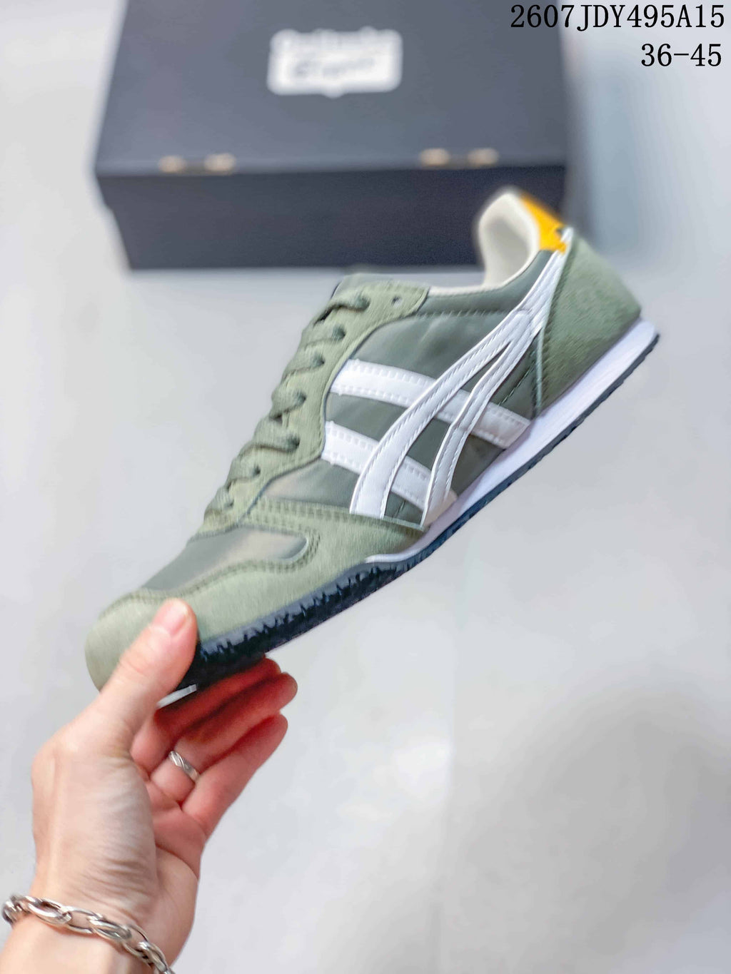 Side view of a green and white Onitsuka Tiger Serrano sneaker showing the contrasting stripes, lace-up construction, and layered sole.
