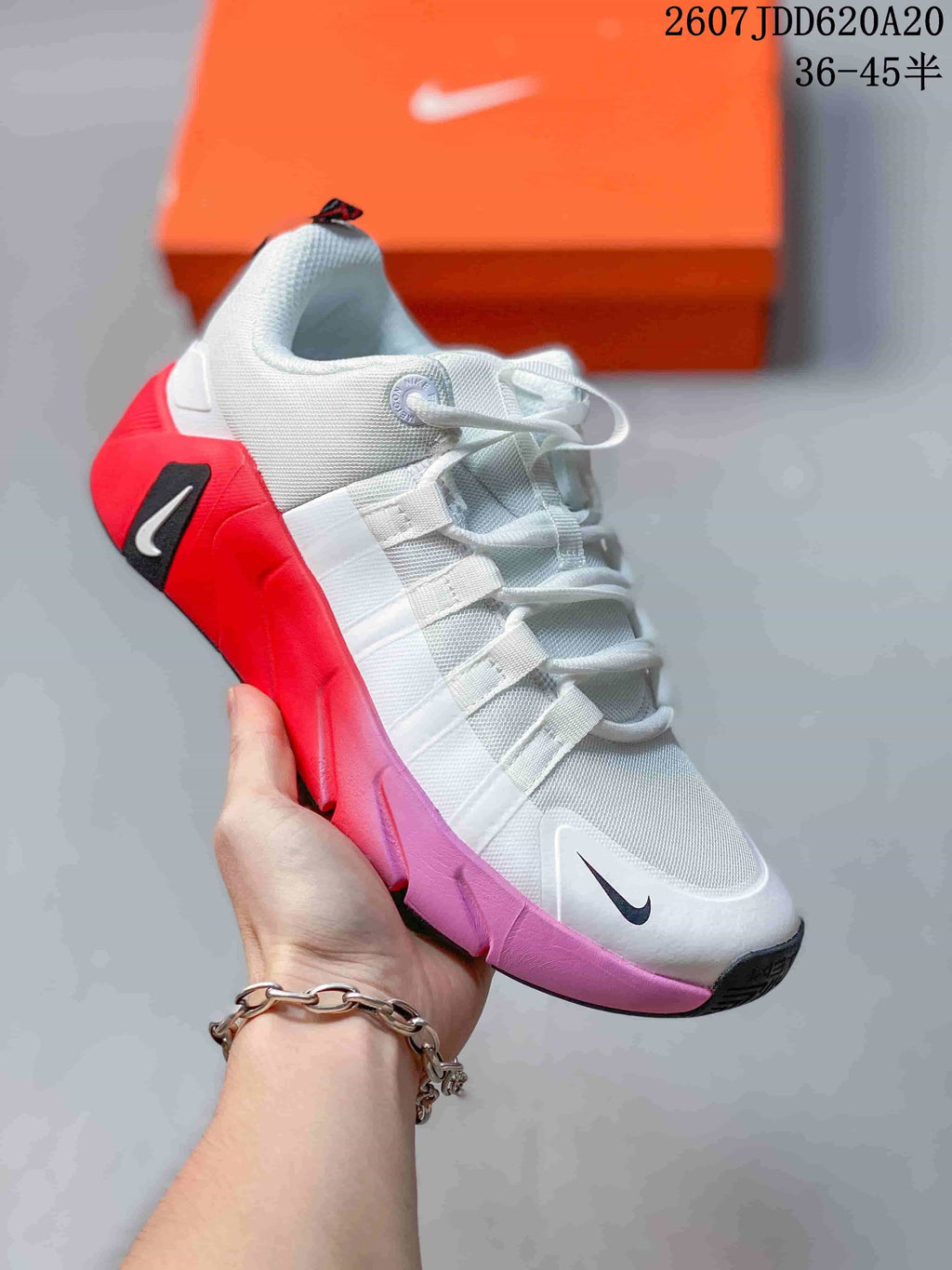 White training sneaker with red and pink sole accents, white laces, layered side straps and a black Nike Swoosh.