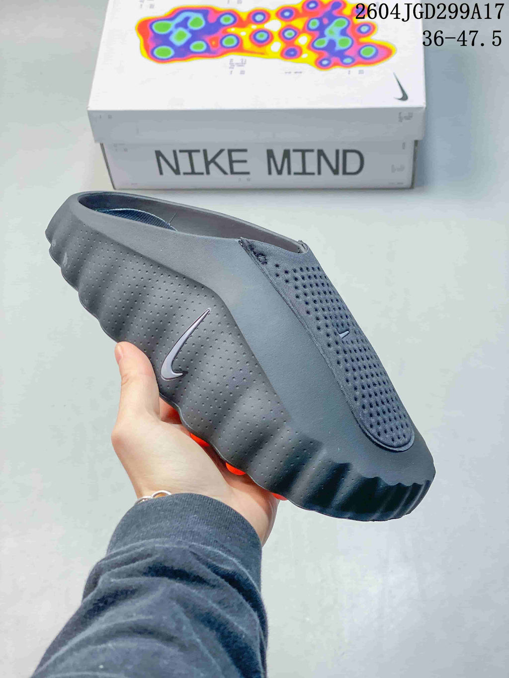 Side view of a black Nike Mind slide showing the perforated upper, side logo, and textured outsole.