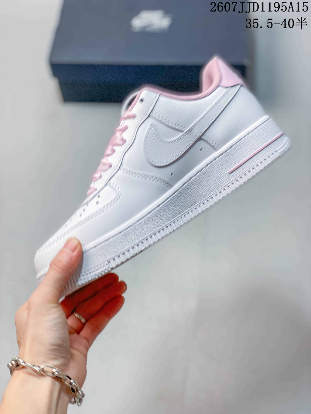 Side view of a white low-top sneaker showing the stitched Swoosh, pink collar trim, and white textured sole.