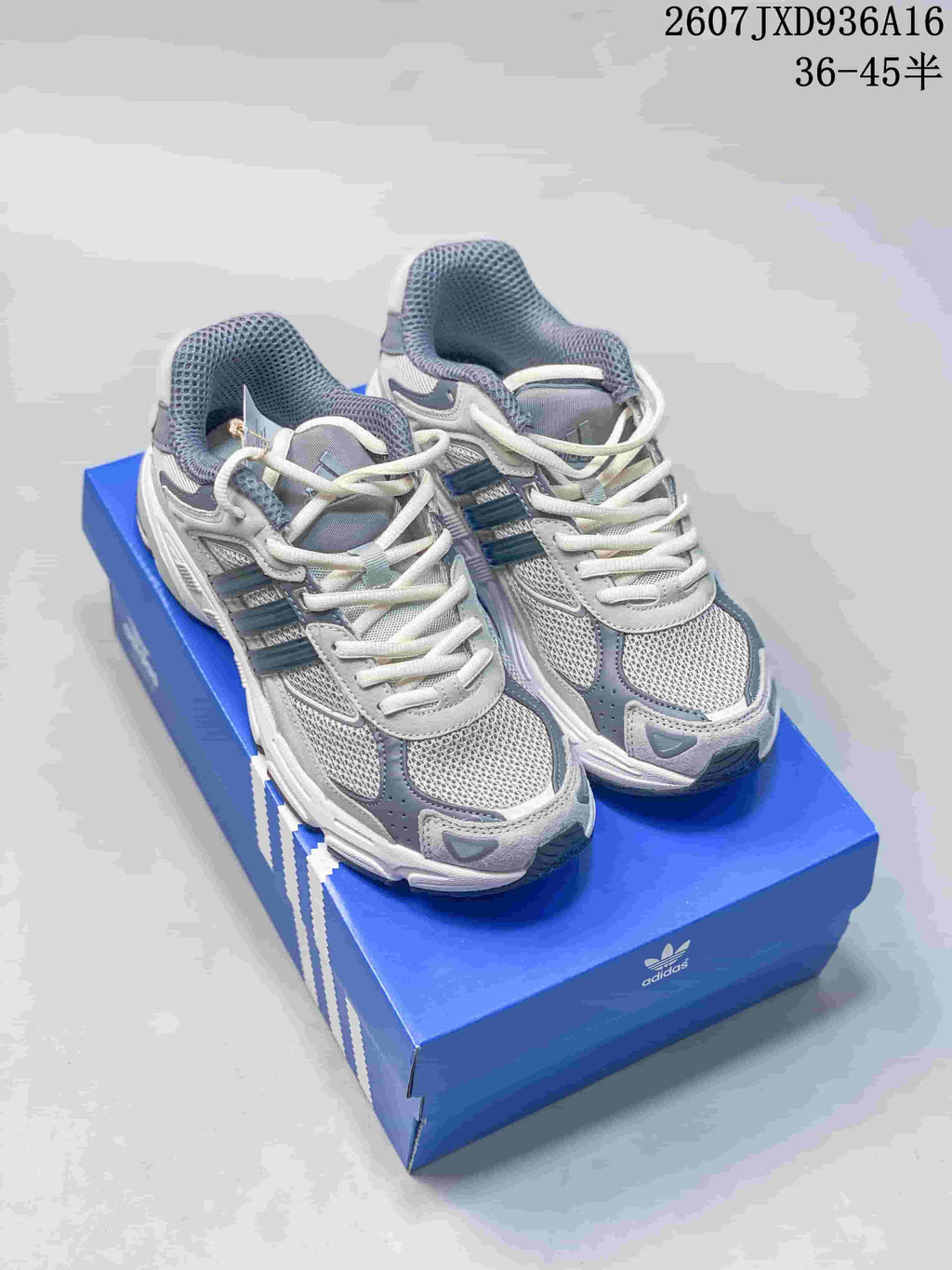 Pair of cream and gray adidas Response CL sneakers displayed on a blue adidas shoe box.