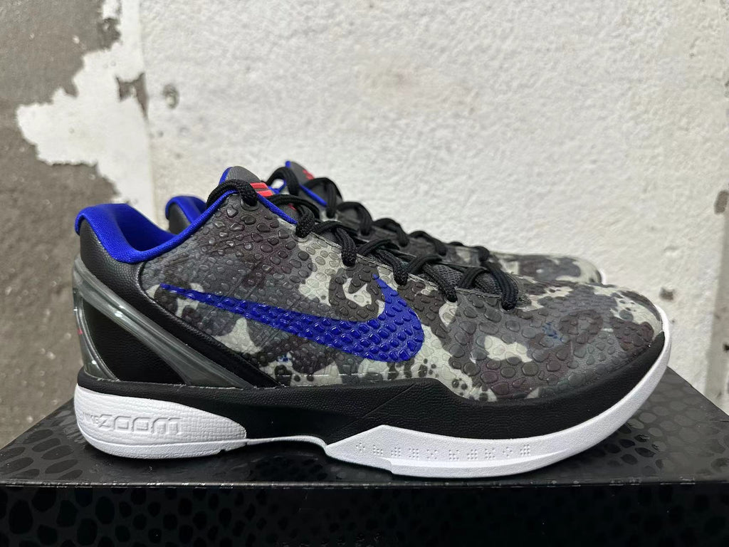 Side view of a gray camouflage Nike basketball shoe with a blue Swoosh and white sole.