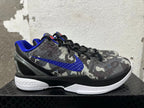 Side view of a gray camouflage Nike basketball shoe with a blue Swoosh and white sole.