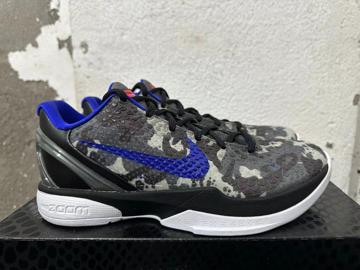 Side view of a gray camouflage Nike basketball shoe with a blue Swoosh and white sole.
