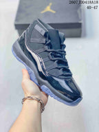 Angled side view of the dark high-top sneaker showing the layered upper, glossy overlays and translucent outsole.