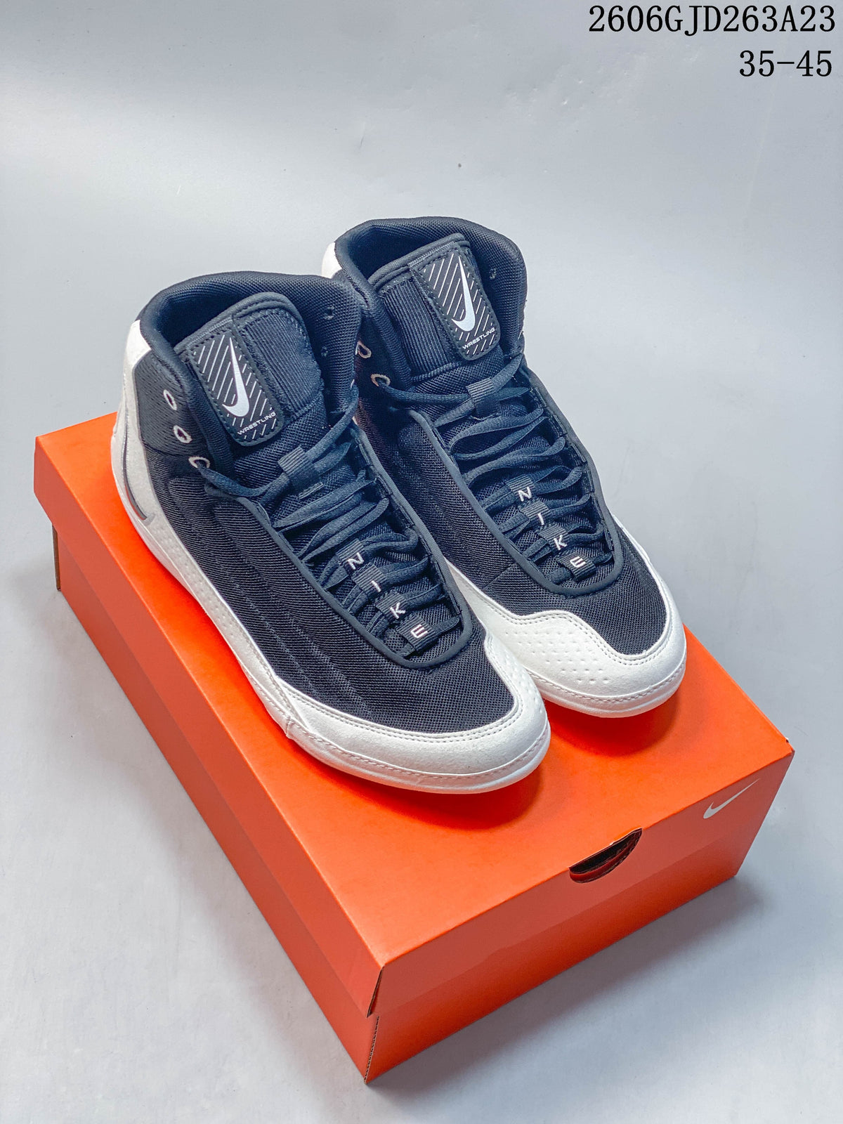 Dark navy Nike Inflict 4 wrestling shoes with white contrast panels, shown on an orange shoe box.