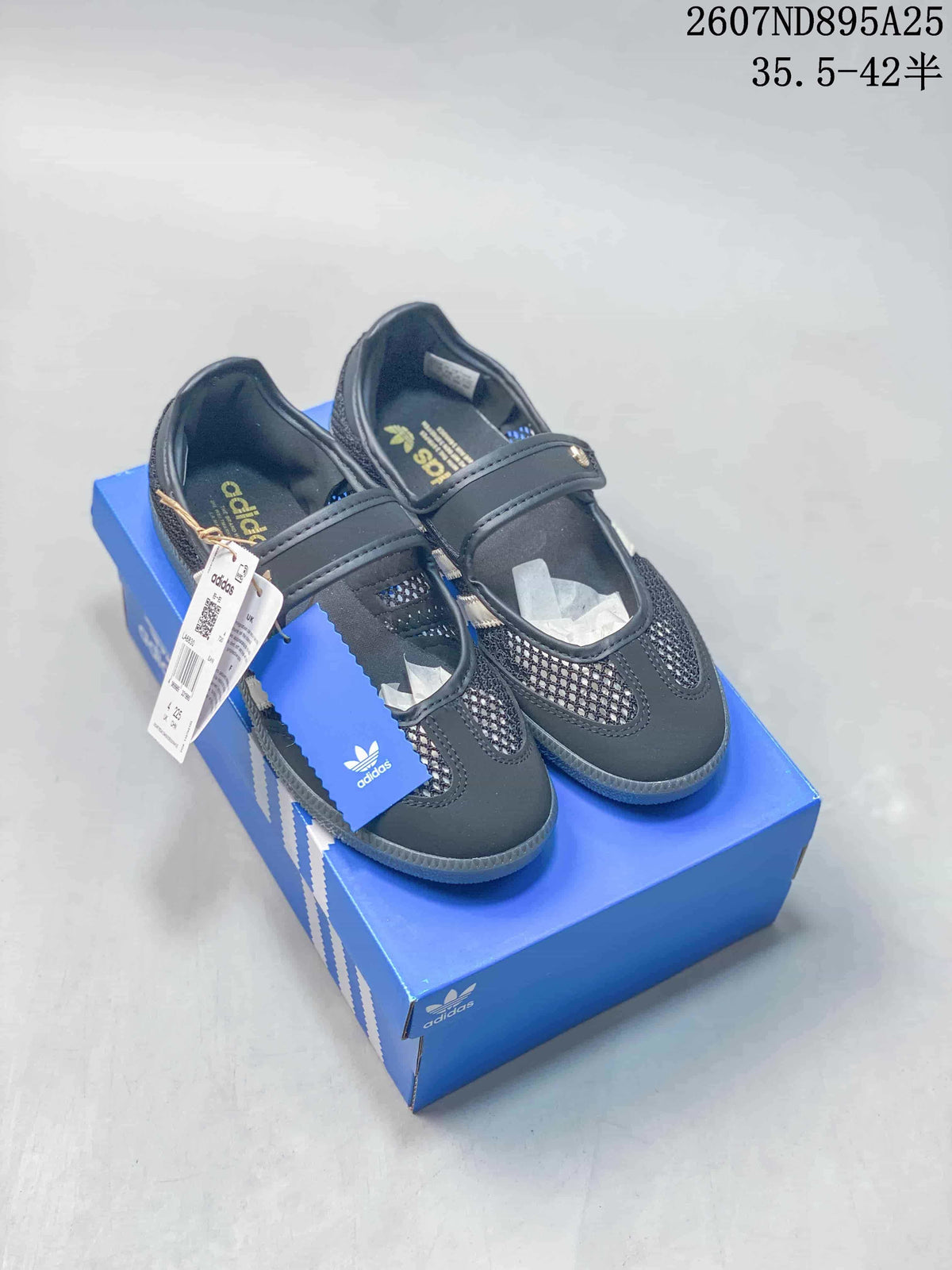 Black adidas Mary Jane-style sneakers displayed on a blue shoebox, showing the strap, mesh panels, and packaging.