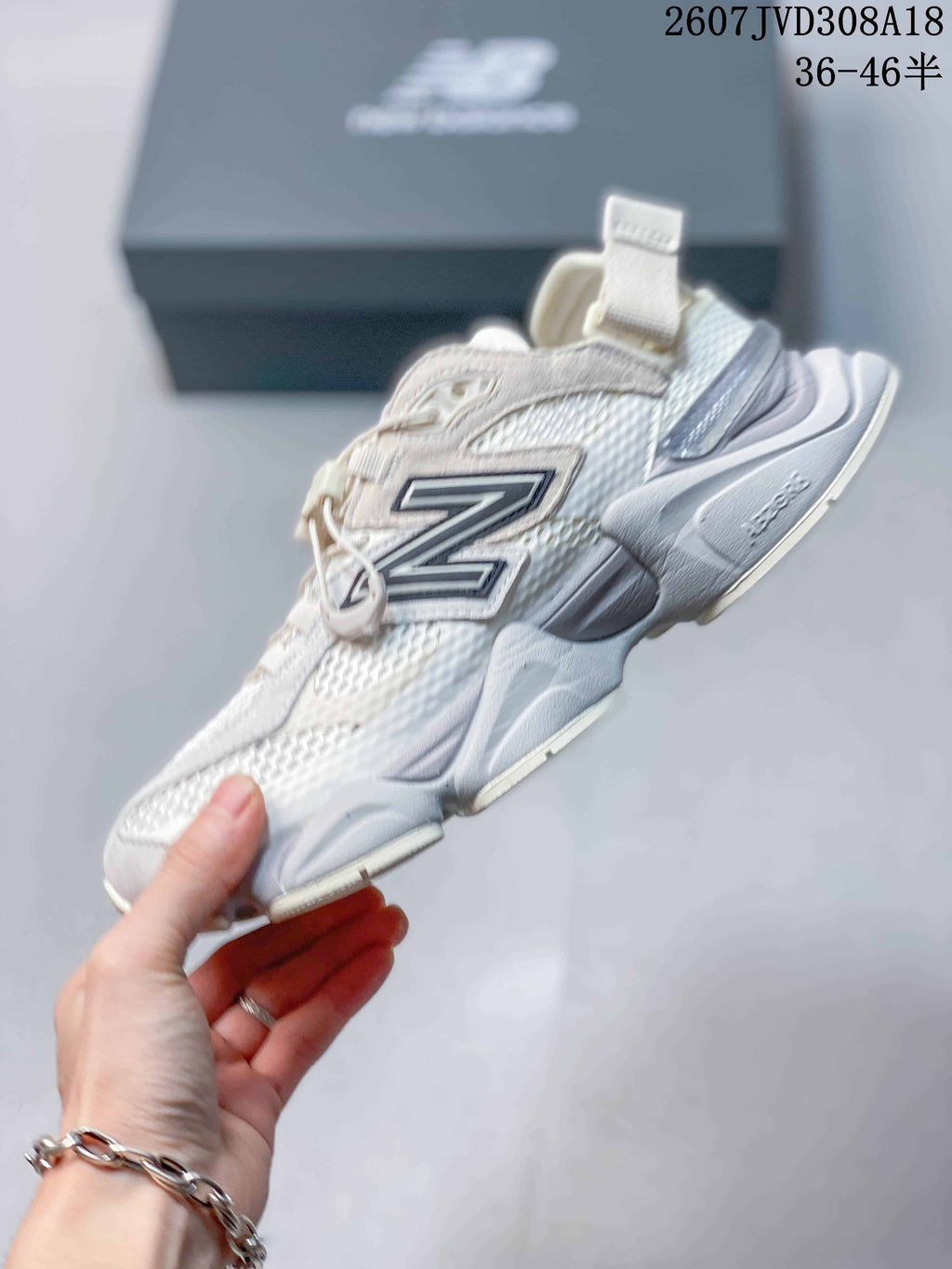 Side profile of a white and light gray New Balance 9060 sneaker showing layered panels, mesh sections, and the sculpted midsole.