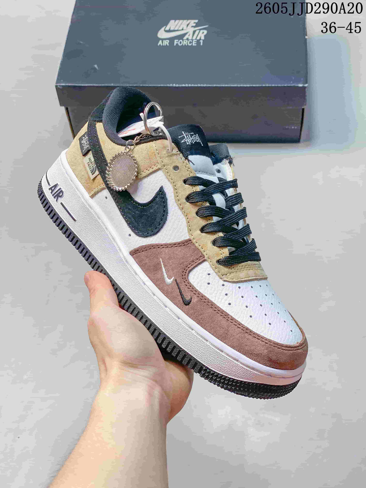 Angled side view highlighting the layered color-blocked upper, black Swoosh, white midsole, black outsole, and attached decorative tag.