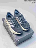 Pair of black and navy Adidas Alphabounce Switch sneakers displayed on a shoebox, with white side details and sculpted light-colored midsoles.