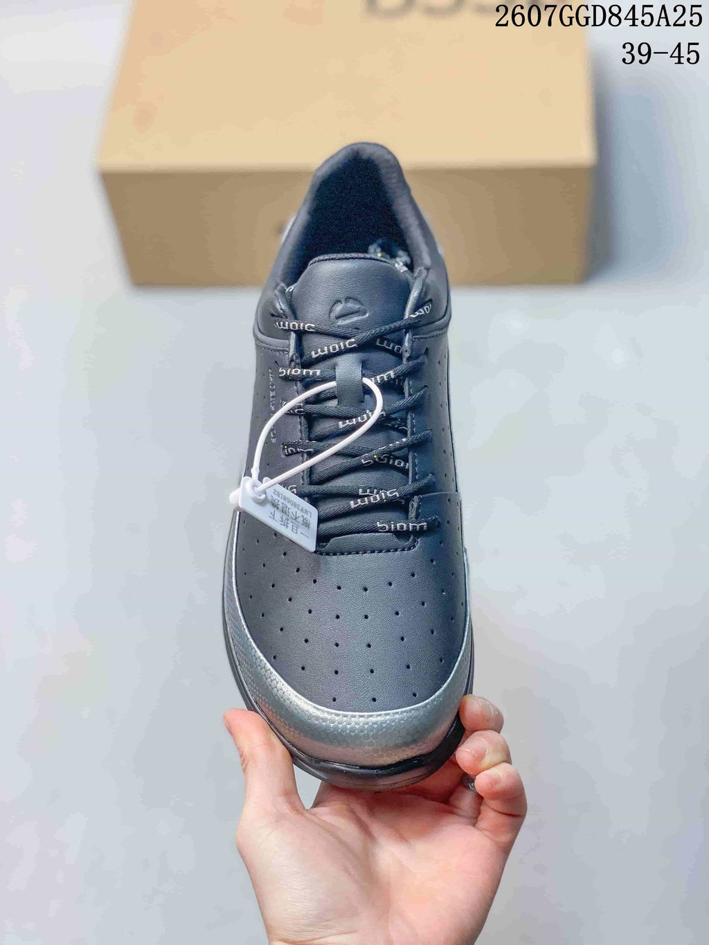 Top view of the black lace-up sneaker showing the perforated toe, padded collar, branded laces, and silver-toned toe trim.
