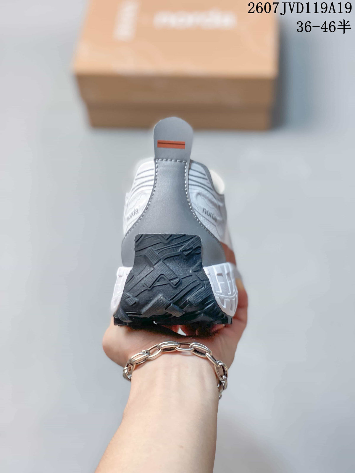 Rear view of the white sneaker showing the gray heel panel, pull tab, and black outsole section.