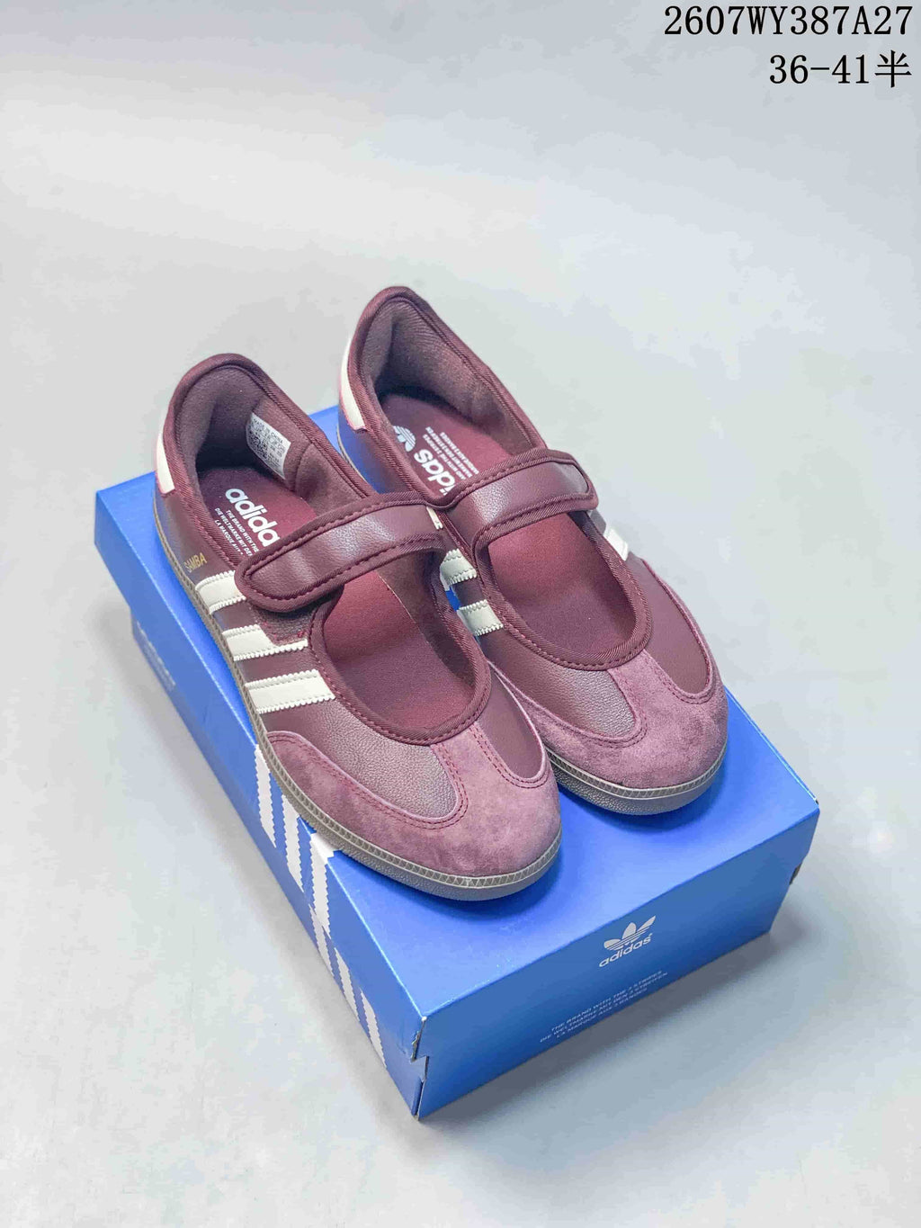 Burgundy Samba Jane sneakers with white stripes and adjustable straps displayed on a blue shoe box.