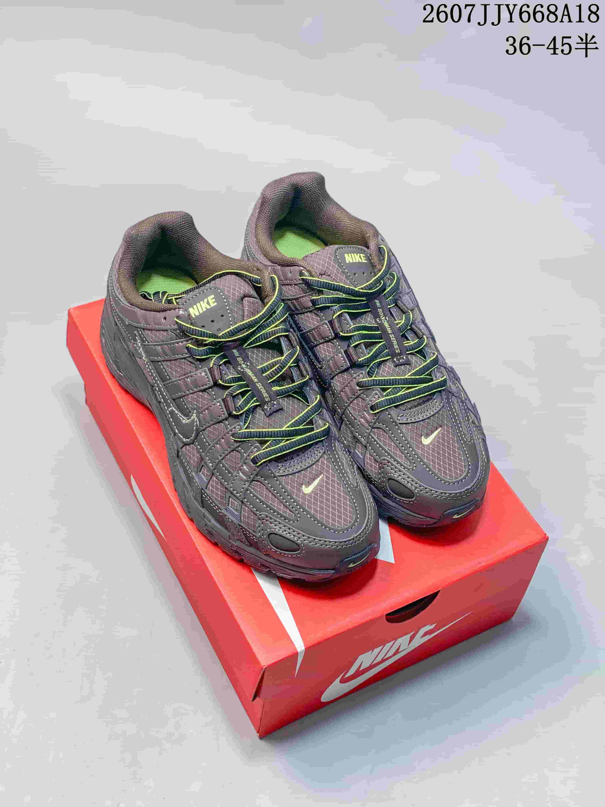 Pair of dark gray Nike P-6000 sneakers with neon green lace accents displayed on a red Nike shoe box.