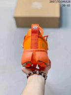 Rear view of an orange sneaker showing the padded heel, pull tab, branded heel detail, and sculpted outsole.