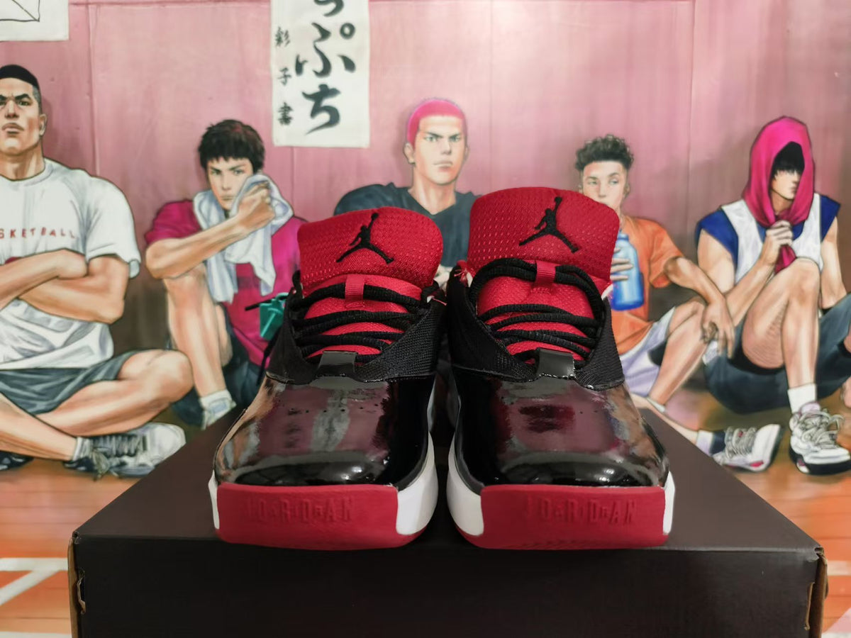 Front view of black and red Jordan sneakers with glossy forefoot panels and red tongues.