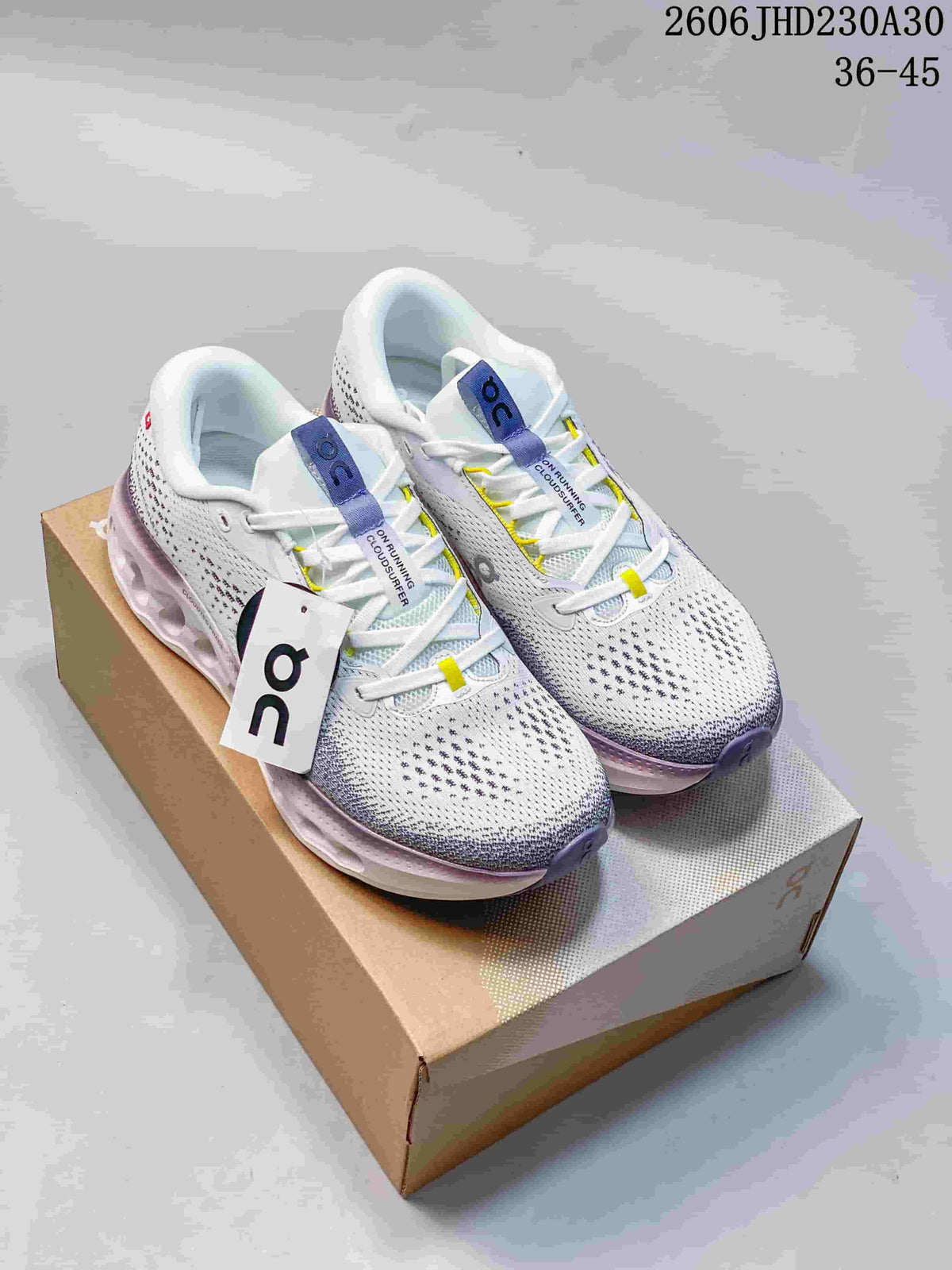 Pair of white On Cloudtilt shoes with purple and yellow accents displayed on a shoebox.