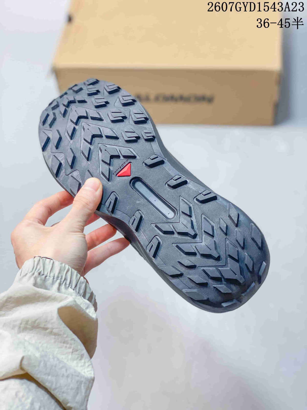 Close view of the Salomon Genesis outsole showing a patterned rubber tread with pronounced directional lugs and a small red detail.