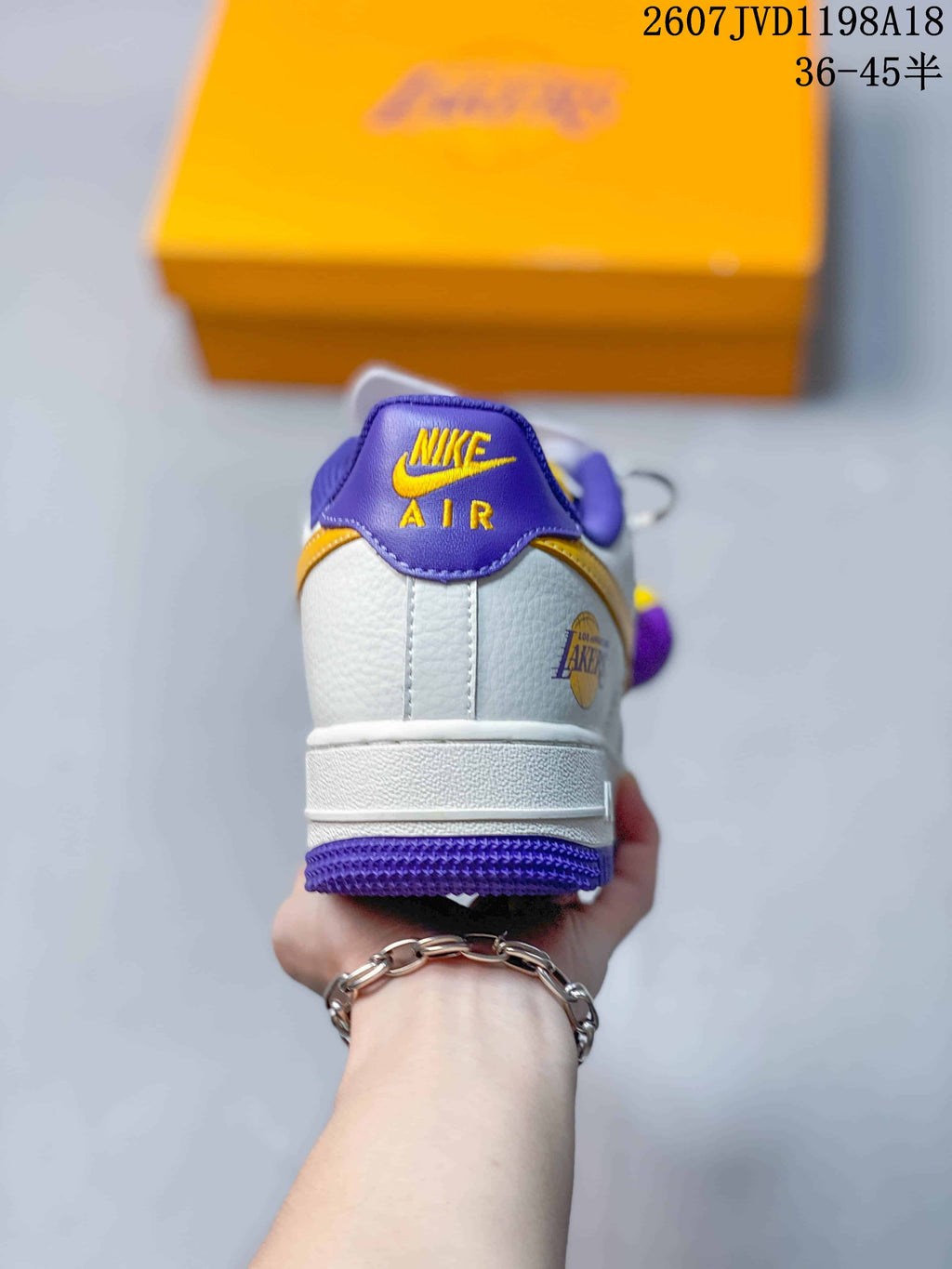 Rear view showing purple heel accents, white panels, and gold and purple outsole sections.