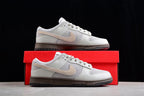 Nike SB sneaker displayed on a red shoebox, showing the beige Swoosh and dark outsole.