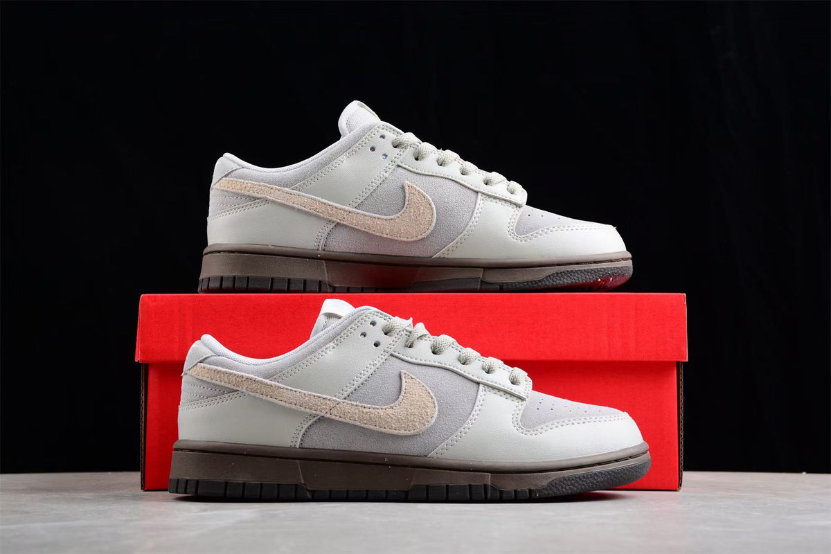 Nike SB sneaker displayed on a red shoebox, showing the beige Swoosh and dark outsole.