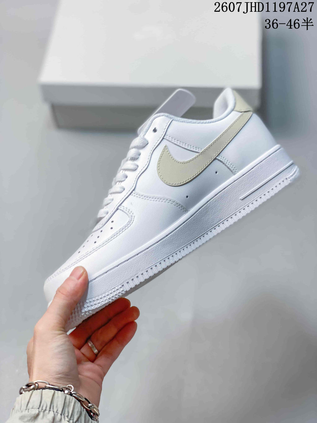 Side view of the white low-top sneaker showing the pale beige Swoosh, perforations, layered panels, and textured outsole.