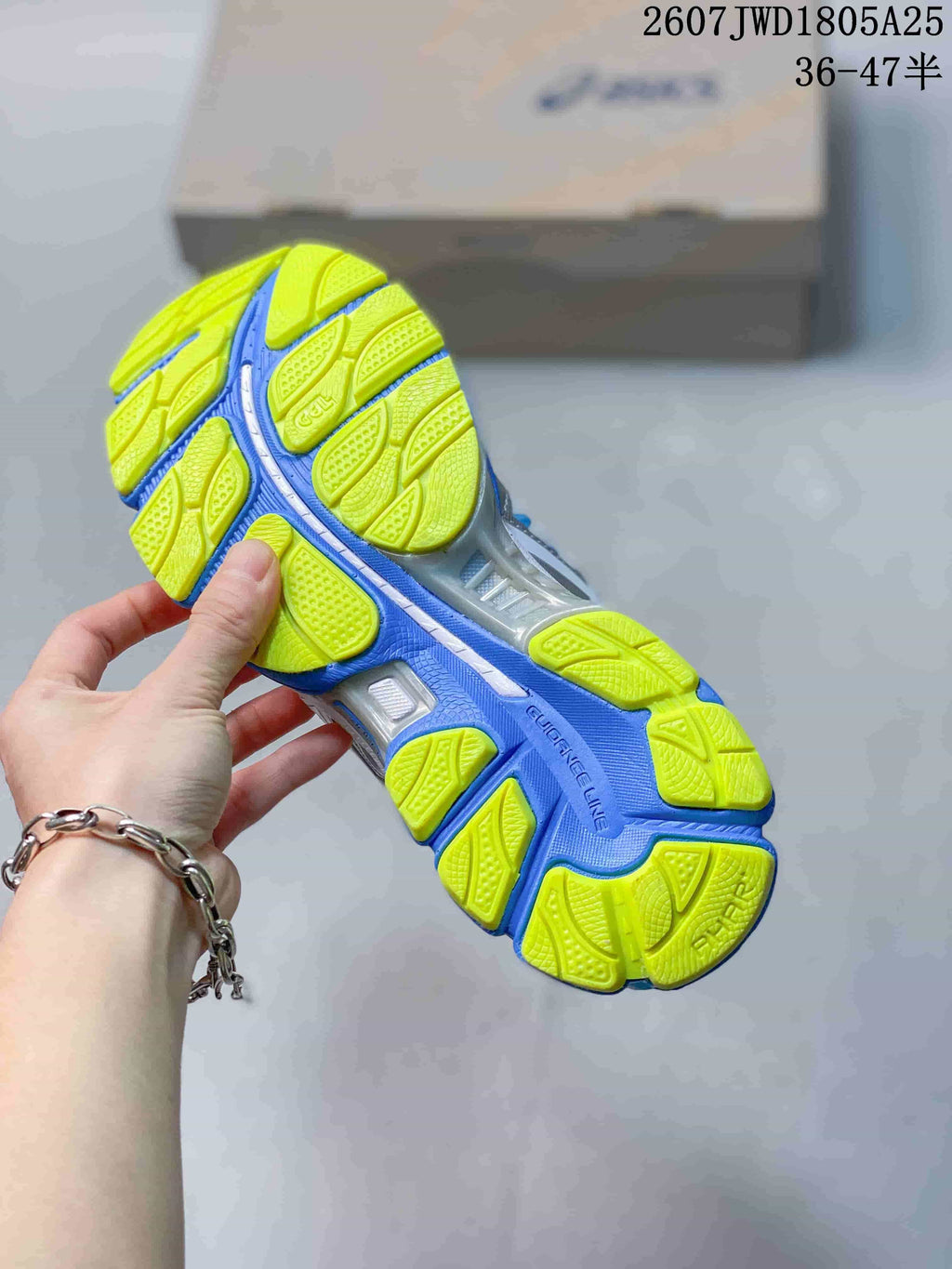 Underside view of an ASICS sneaker showing the segmented neon yellow and blue outsole tread.
