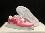 Angled view of the pink BAPE Sta sneakers with one shoe lifted to show the white patterned outsole and central star detail.