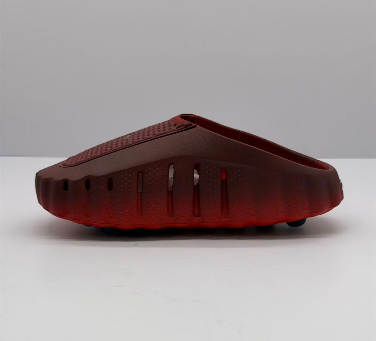 Side profile showing ventilation openings along the dark red sneaker upper and black outsole elements.