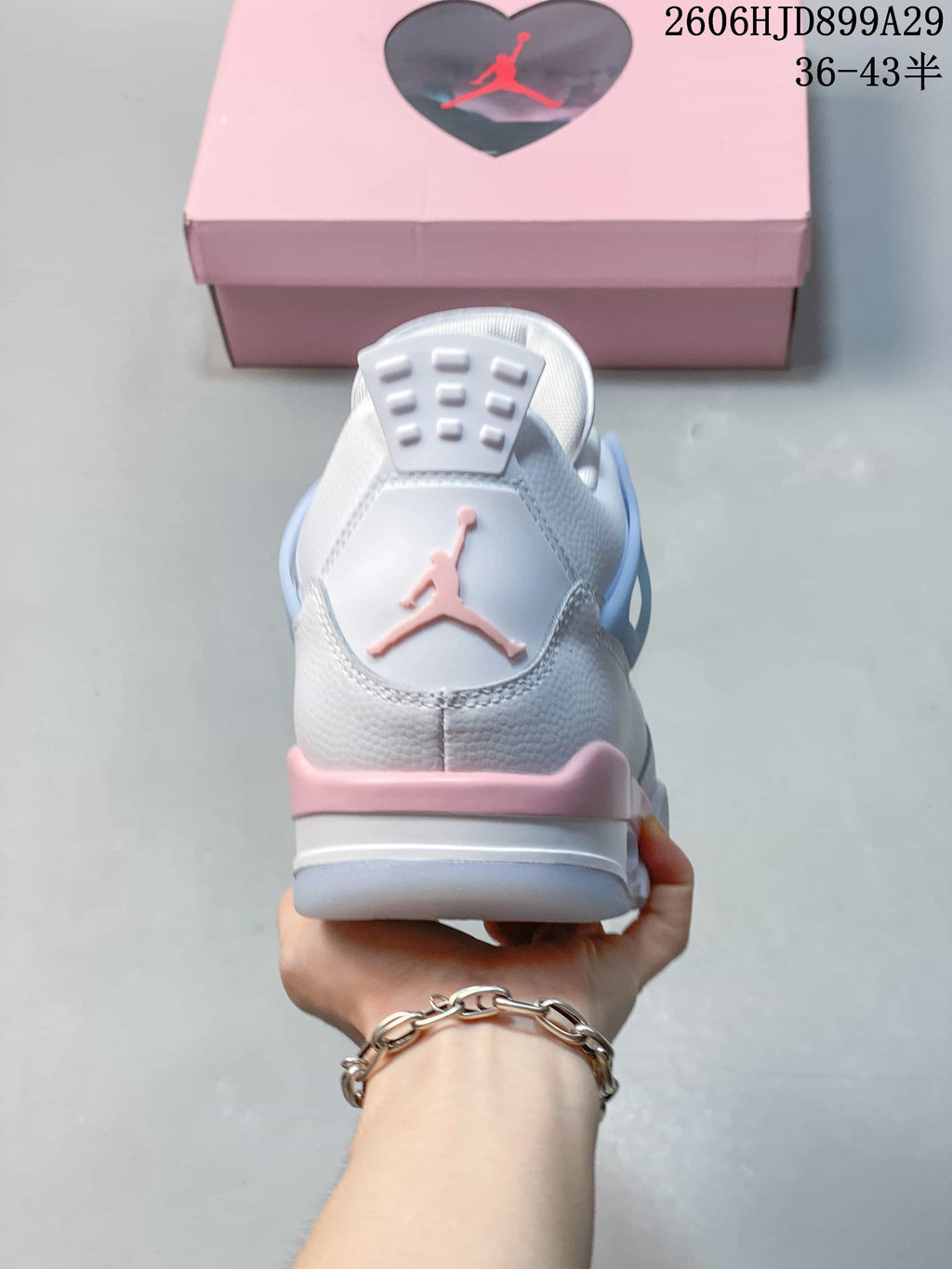 Rear view of a white Air Jordan 4 Retro sneaker with pink and pale blue details