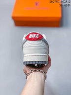 Rear view of the sneaker showing the red Nike heel tab, white heel panel, layered stitching, and gray outsole edge.
