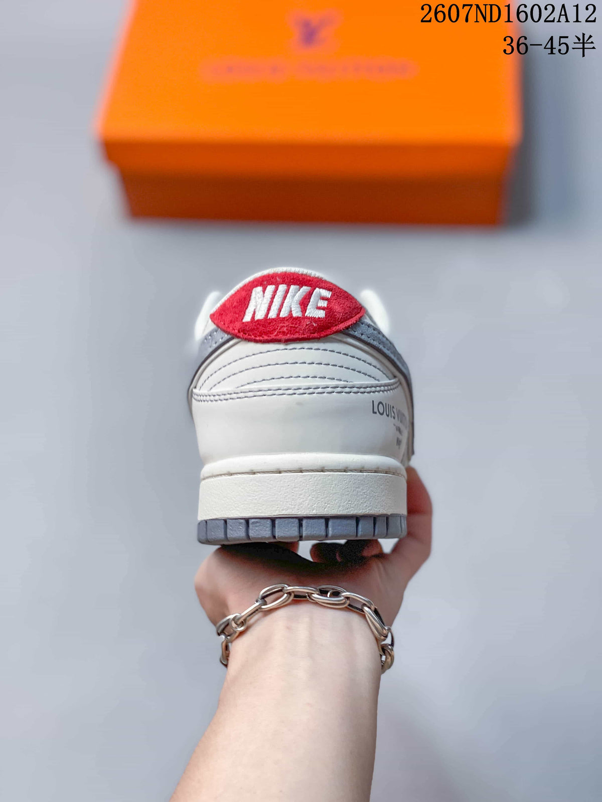 Rear view of the sneaker showing the red Nike heel tab, white heel panel, layered stitching, and gray outsole edge.