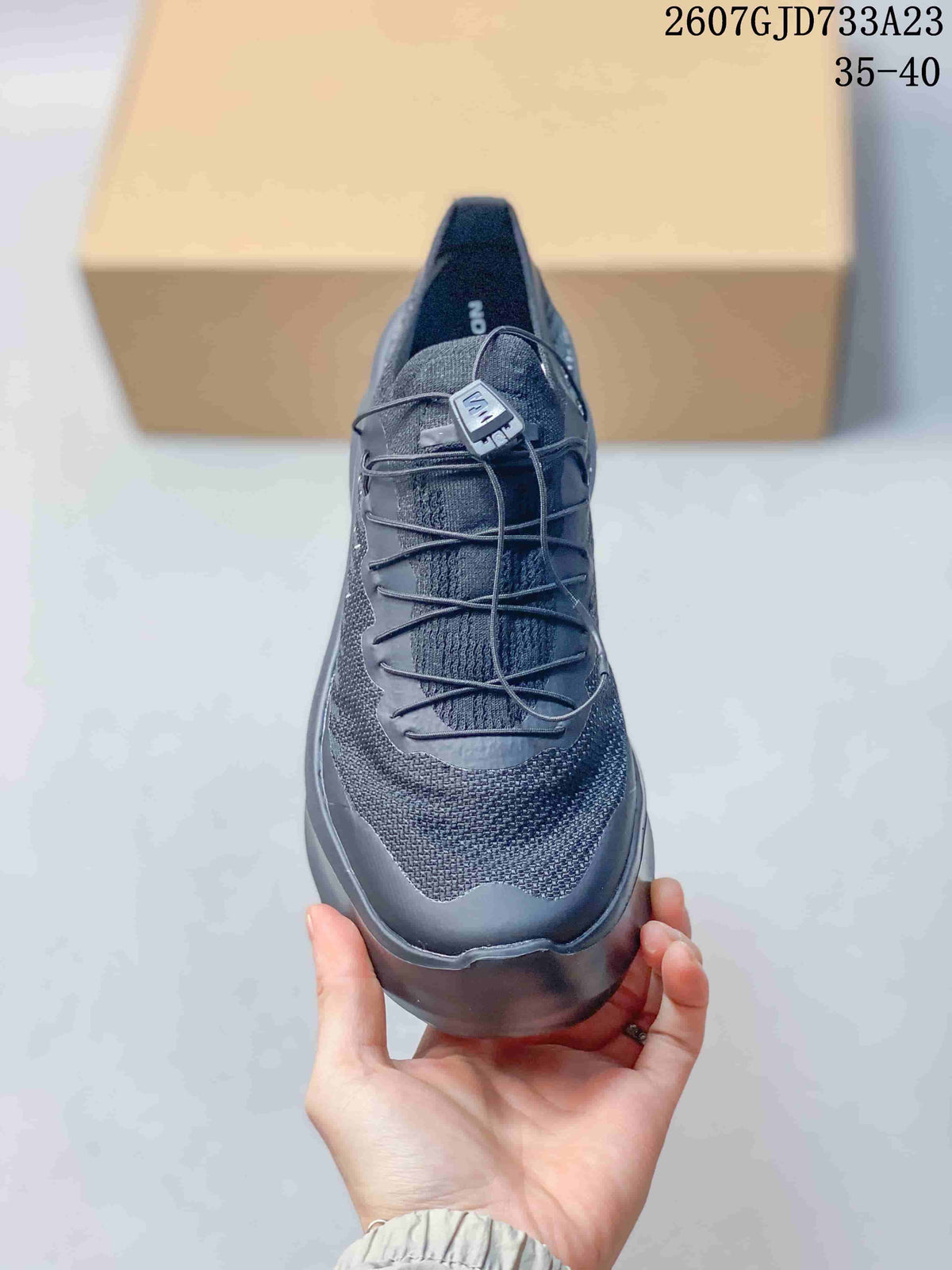 Front view of the black sneaker showing the textured upper, cord-style lacing, and rounded toe.