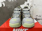Front view of gray Nike sneakers with brown side panels, lime Swooshes and light lime soles.