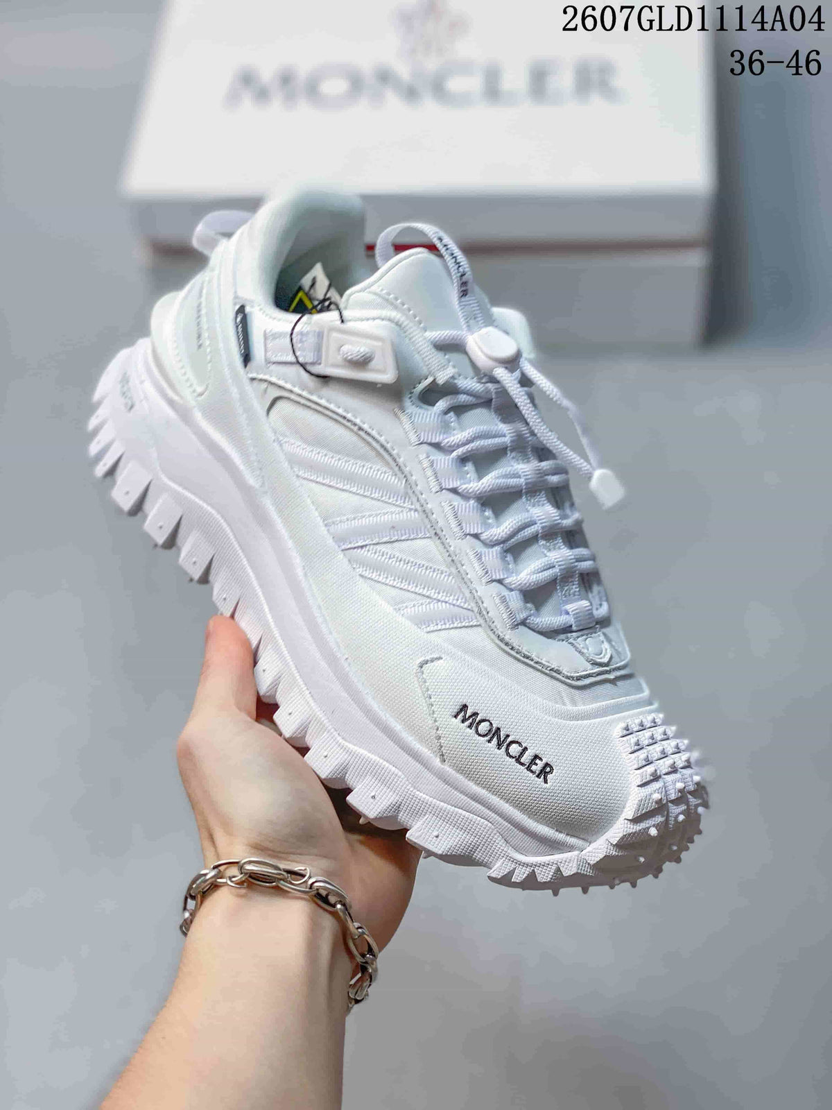 Angled front-side view of the white sneaker showing Moncler branding, textured upper panels and a thick lugged outsole.