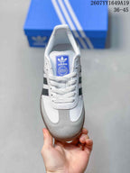Top view showing white laces, blue adidas tongue label, gray textured toe panel, and white upper.