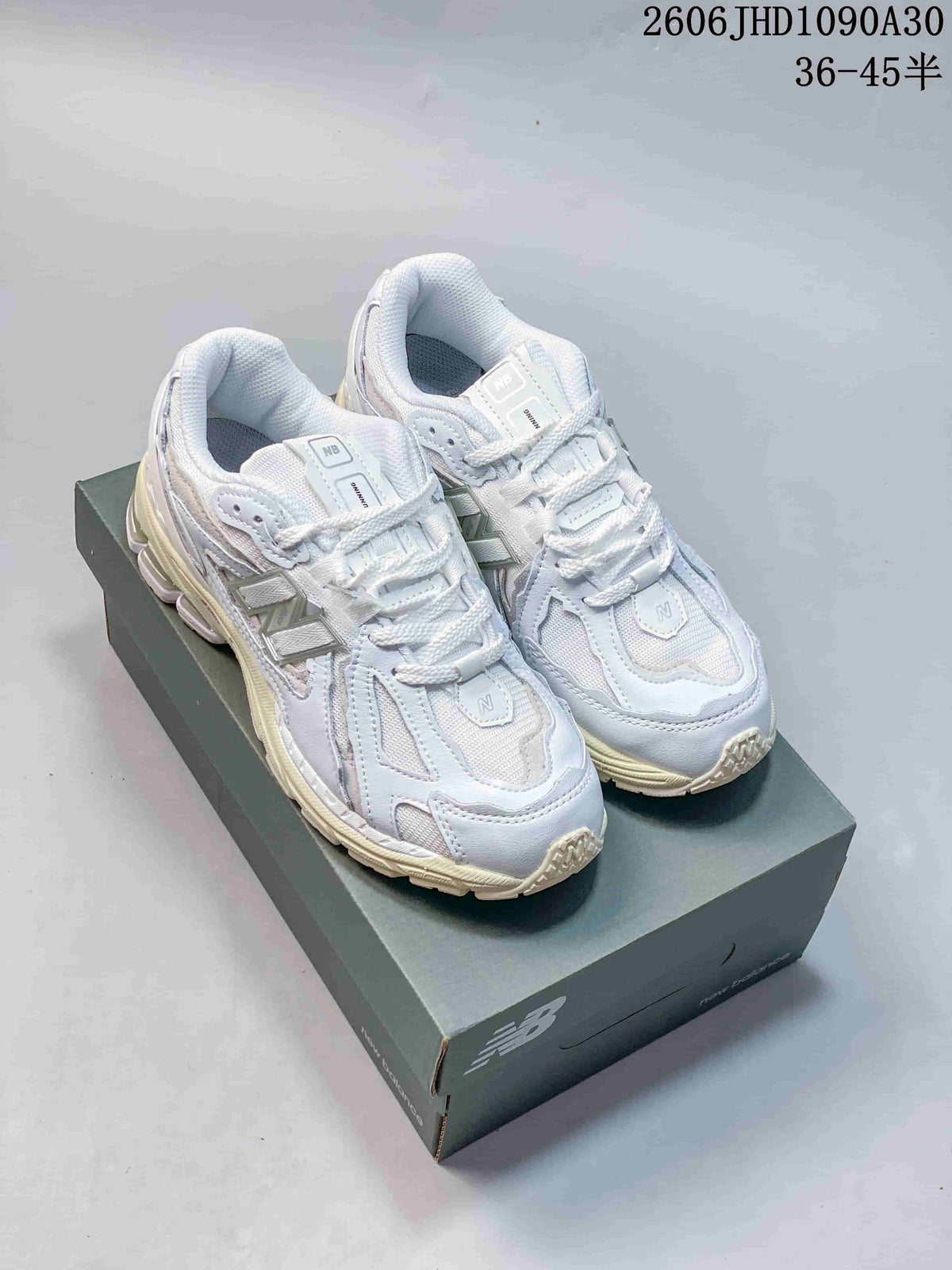 Pair of white and silver-toned New Balance M1906R sneakers on a shoebox; image overlay shows size range 36–45.5.